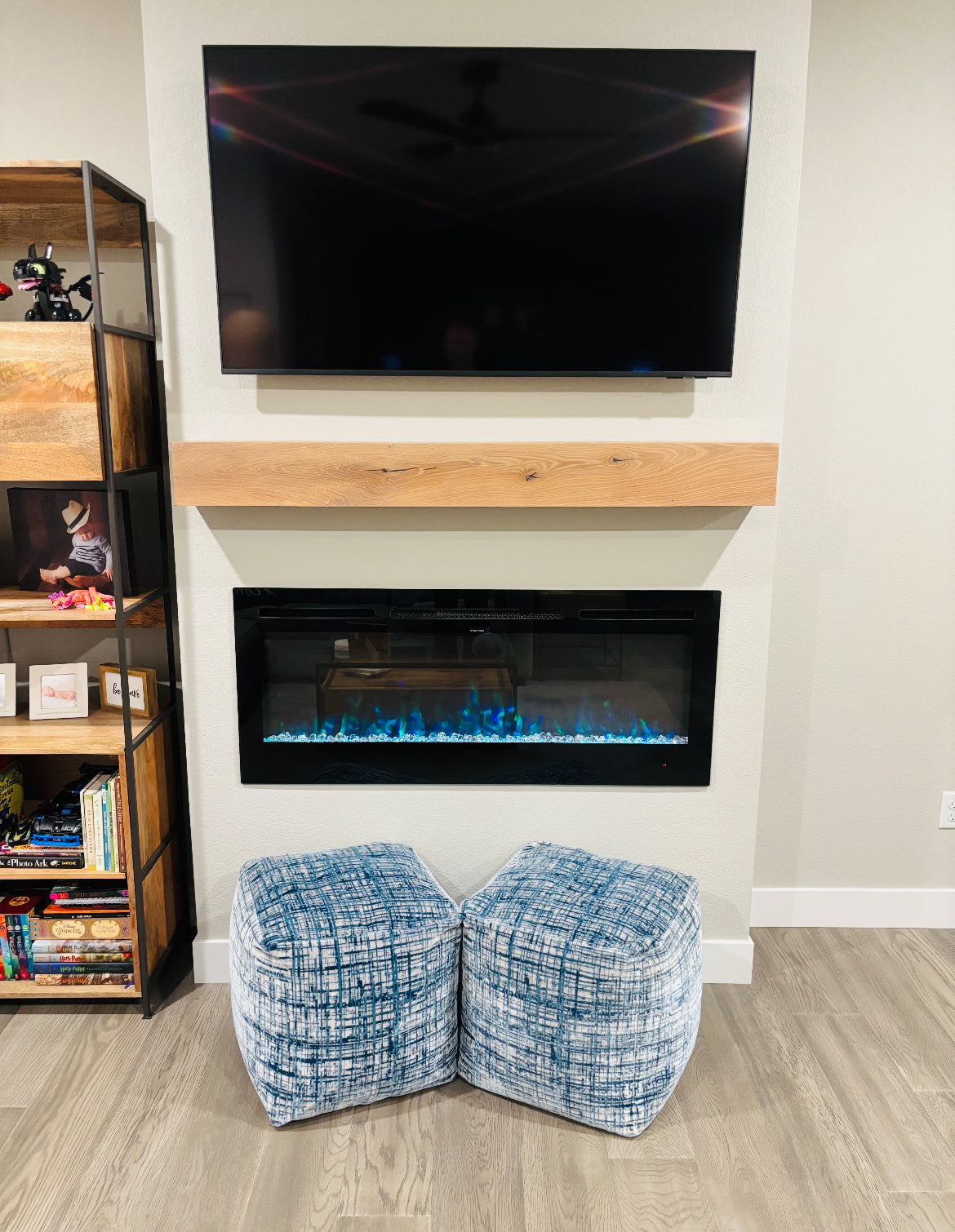 Modern living room with electric fireplace, TV, and wooden mantel.