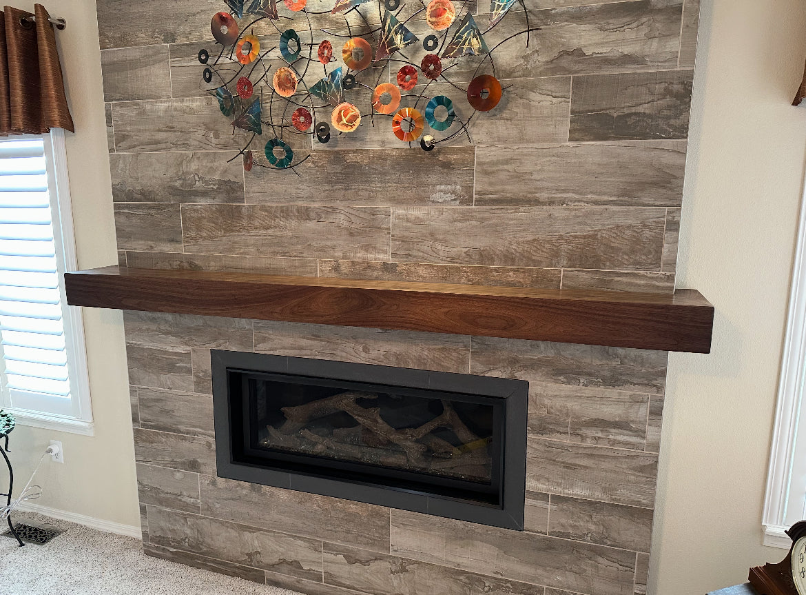 Modern fireplace with wooden mantel and decorative glass art above it.
