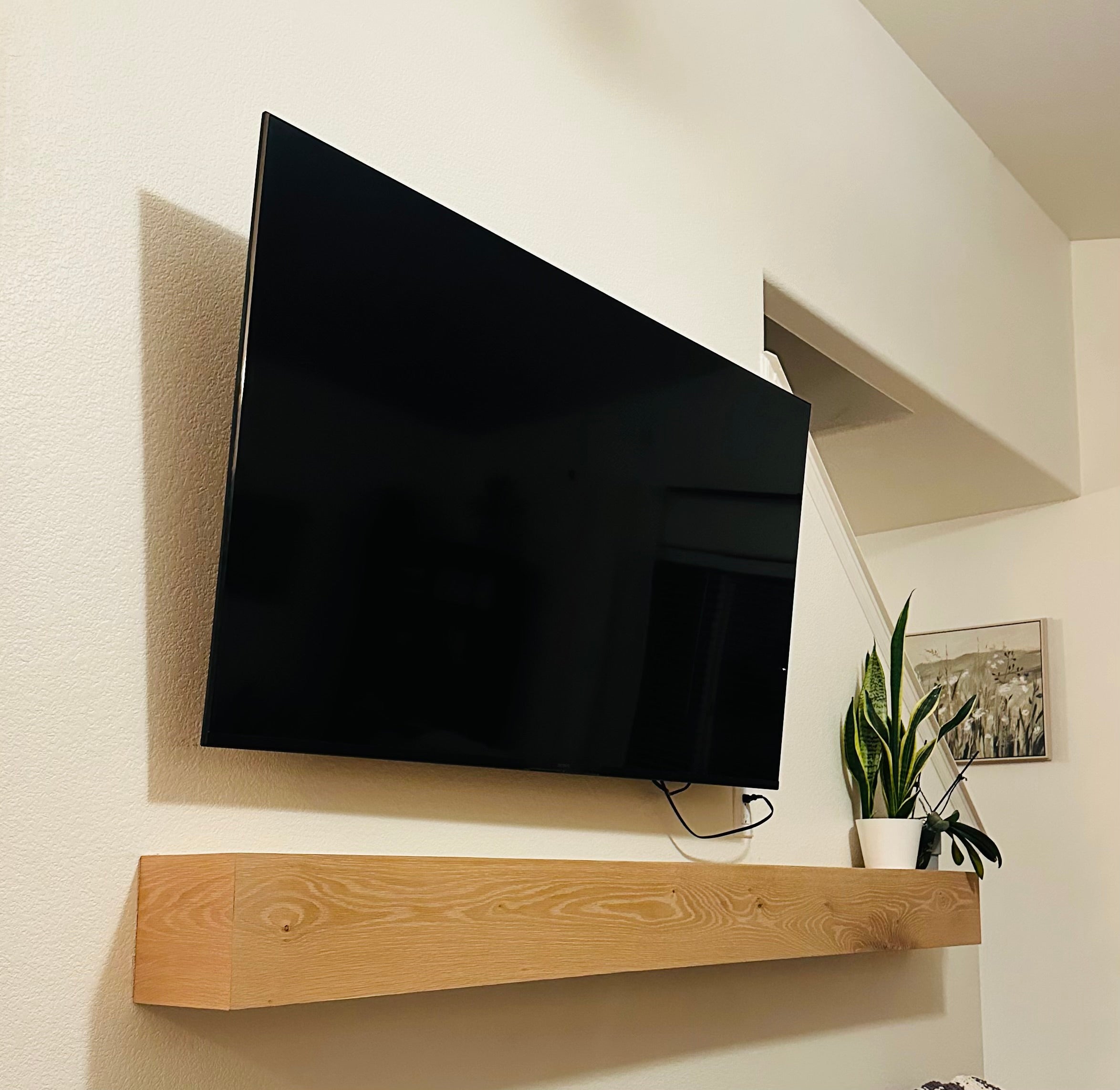 Modern living room with a large flat-screen TV mounted on the wall above a wooden mantel.
