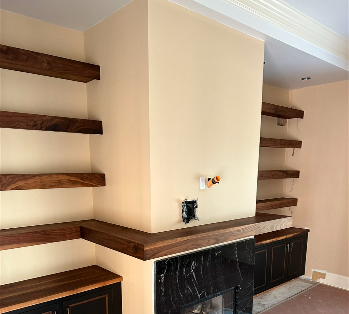 Wooden shelves against a beige wall with a black fireplace.